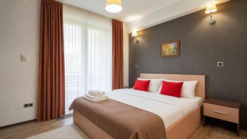 a bedroom with a large bed with red pillows at TIAM Apartment Poiana Brașov D117, 3 rooms, 3 terraces, 3 bathrooms in Poiana Brasov