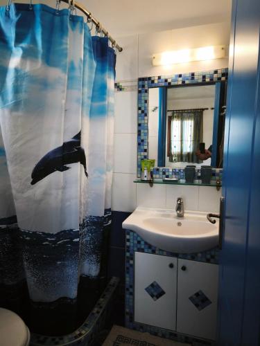 a bathroom with a sink and an umbrella shower curtain at Ammoudia Studios in Agiassos