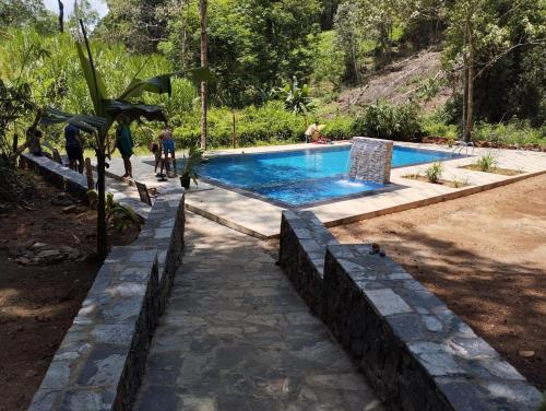 a swimming pool with people standing around it at Makelioya Nature Resort in Kelinkanda