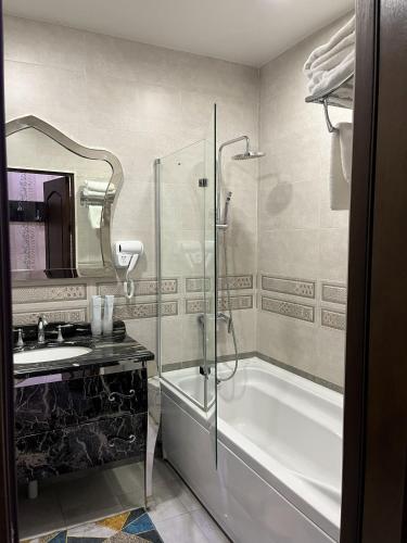 a bathroom with a shower and a tub and a sink at Sunrise Apartments in Dushanbe