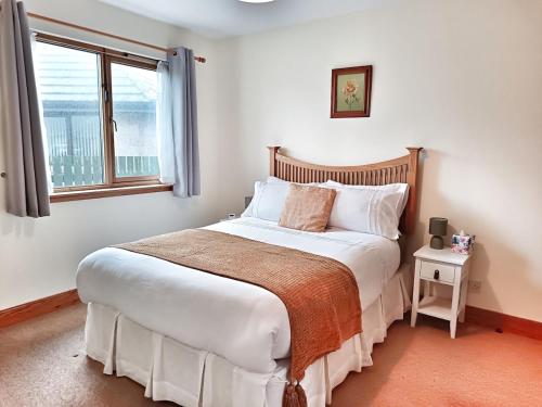 a bedroom with a large white bed with a window at Golf View, Cruden Bay in Cruden Bay