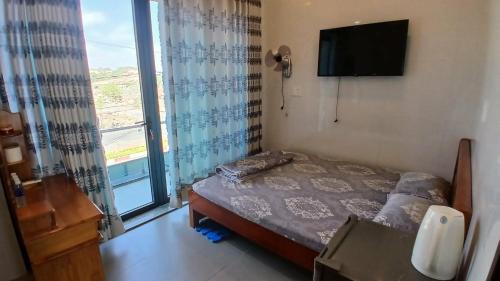 a bedroom with a bed and a tv and a window at Hotel Hương Phong in Binh Chau