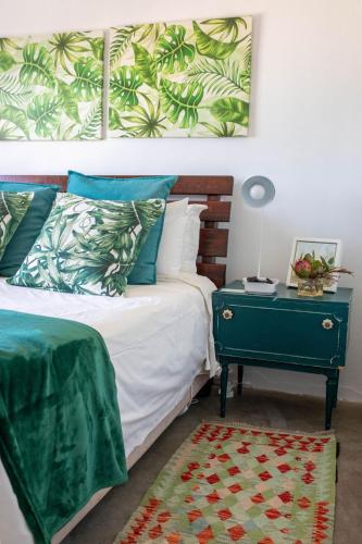 a bedroom with a bed with a green end table at Stay At Friends in Bettyʼs Bay