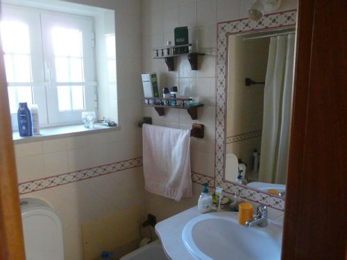 a bathroom with a sink and a mirror and a toilet at Casa do Castelão in Loulé