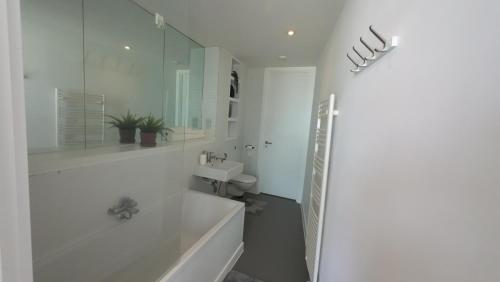 a white bathroom with a tub and a toilet at Nirankaar peace 1bhk in Birmingham