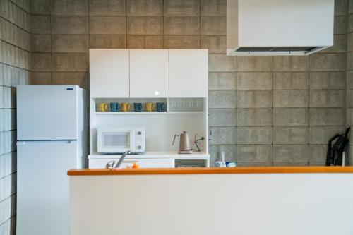 eine Küche mit weißen Schränken und einem weißen Kühlschrank in der Unterkunft vividテラス101 in Miyako-jima