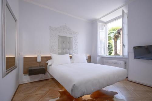 a white bedroom with a large bed and a tv at Caffè dell'Arte Boutique Rooms Locarno in Locarno