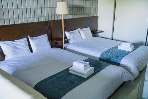 zwei Betten in einem Hotelzimmer mit Handtüchern darauf in der Unterkunft vividテラス101 in Miyako-jima