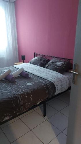 two beds in a room with a pink wall at Casanova home in Saint-Denis