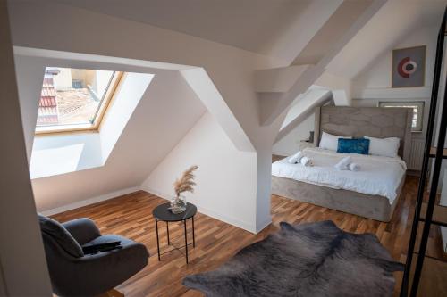 a attic bedroom with a bed and a chair at Barrique 13 - Breakfast at Restaurant & Minibar - Old Town in Braşov