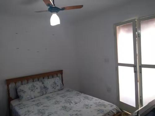 a bedroom with a bed with a ceiling fan and a window at Suites-II no centro de Salto SP in Salto