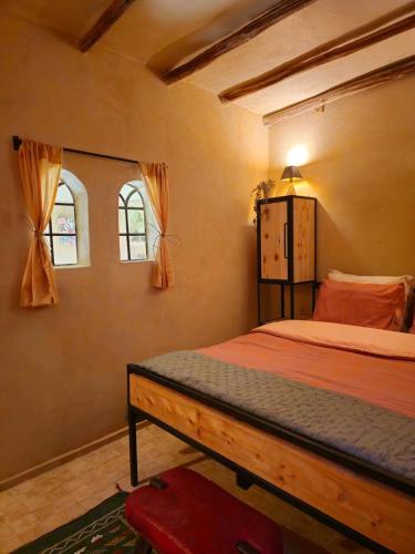 a bedroom with a bed and two windows at Dar Zaytoun Bhalil in Bhalil