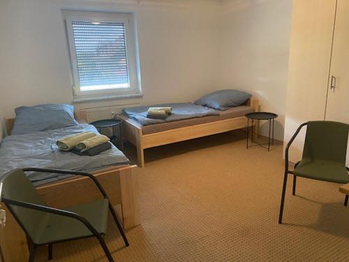 a room with two beds and chairs and a window at WORK & Rest Monteurzimmer in Batzhausen