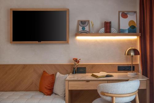a room with a desk with a television on the wall at Hôtel Burdigala by Inwood Hotels in Bordeaux