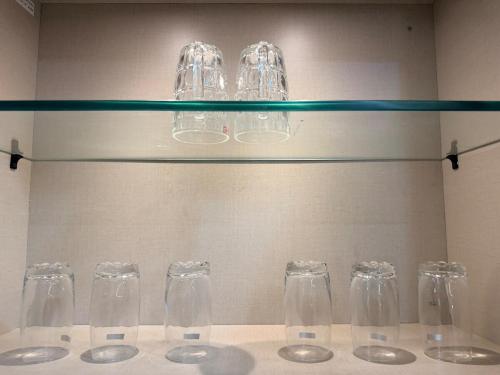 a row of wine glasses sitting on a glass shelf at Veechi Retreat in Secunderabad