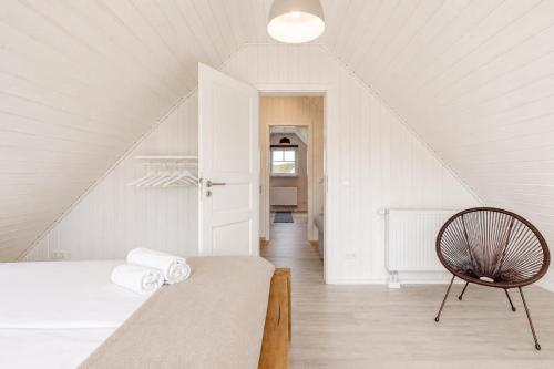 a white bedroom with a bed and a chair at Schiller in Wandlitz