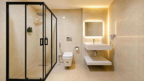 a bathroom with a shower and a toilet and a sink at BAZ Hotel University District in Baghdād