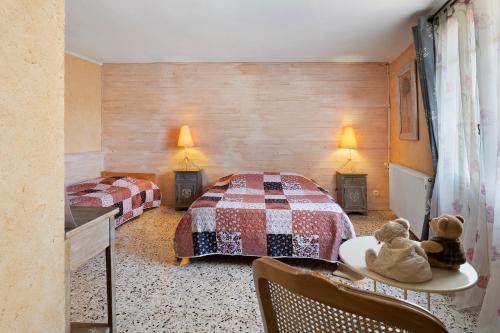 a bedroom with two beds and two teddy bears on a table at Le Clos Mazerolles in Cruzy