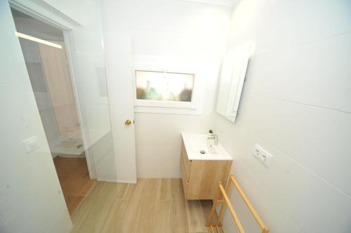 a white bathroom with a sink and a mirror at casa Bayer in Benicàssim