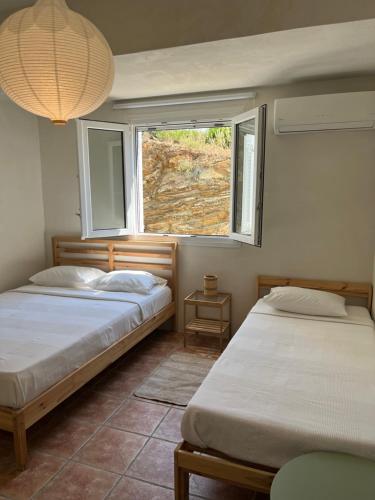 two beds in a room with a window at Salt & Sun Terrace Seafront in Agioi Apostoli