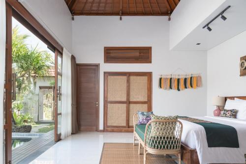 a bedroom with a bed and a sliding glass door at Dijero at Umah Bali in Ubud