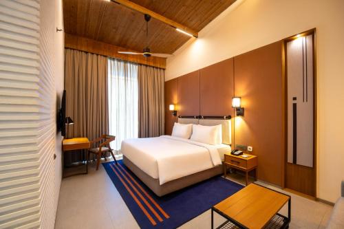 a hotel room with a white bed and a table at Radisson Resort and Spa Lonavala in Lonavala
