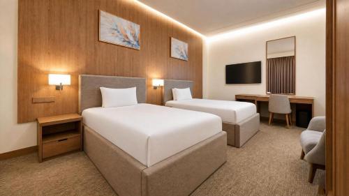 a hotel room with two beds and a desk at BAZ Hotel University District in Baghdād