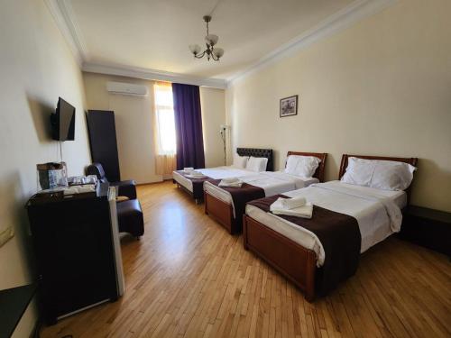 a hotel room with two beds and a television at Nana Grand Hotel Yerevan in Yerevan