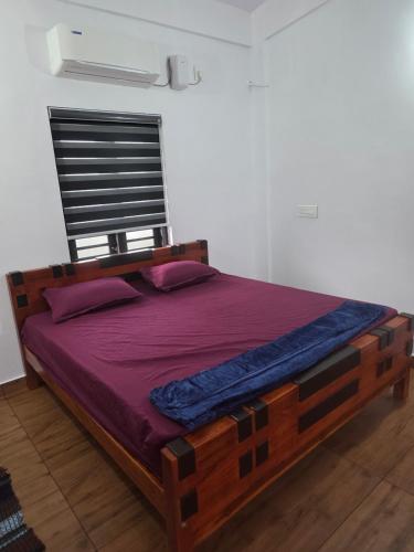 a bedroom with a wooden bed with purple sheets at Ruby Residency in Perintalmanna