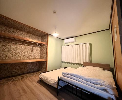 a small bedroom with a bed and a window at Frasis in Furano