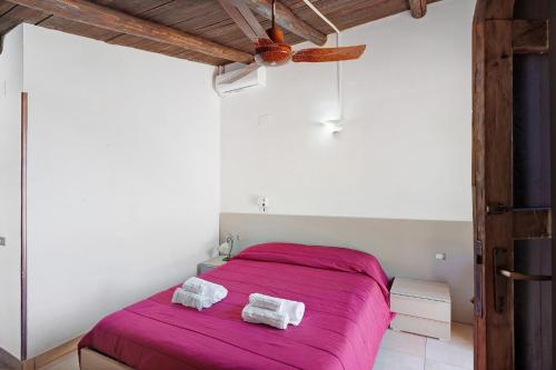 a bedroom with a pink bed with two towels on it at Tenuta Donna Carmela in Pisciotta