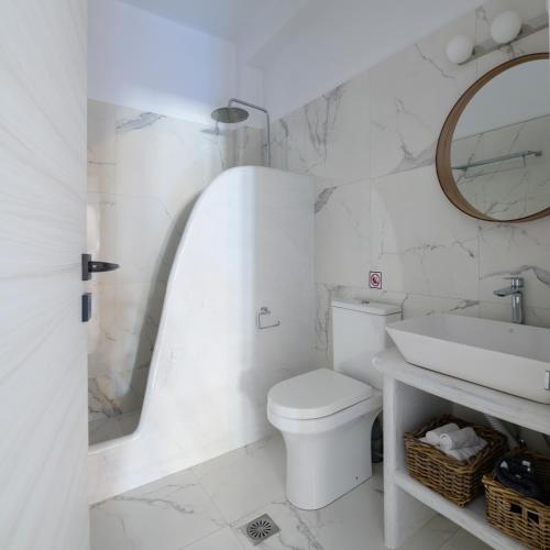 a white bathroom with a sink and a toilet at Santana Apartments in Perivolos