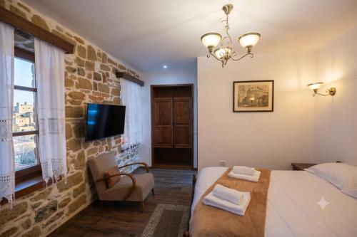 a bedroom with a bed and a tv on a brick wall at Vila e Mjeshtrit in Korçë