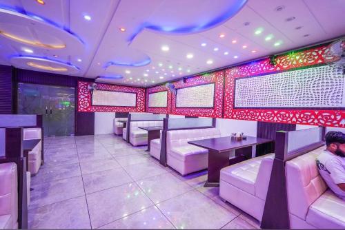 a restaurant with white chairs and tables and red lights at Hotel Crown Plaza in Hoshiārpur