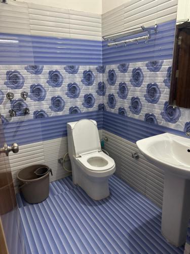 a blue and white bathroom with a toilet and a sink at Hotel Crown Plaza in Hoshiārpur
