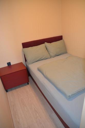 a small bedroom with a bed and a red nightstand at Merķeļa apartamenti in Valka