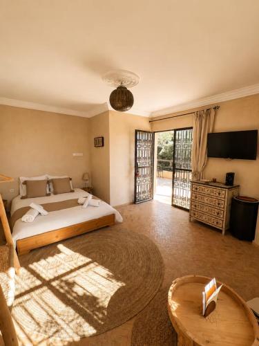 a bedroom with a bed and a television and a table at Maison Zina in Al Ghar