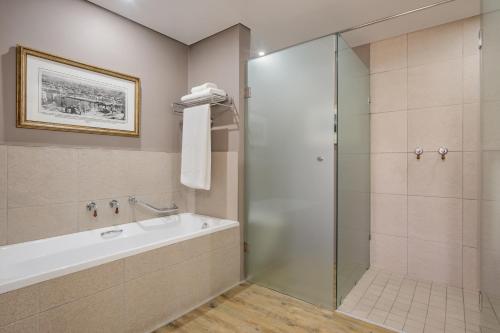 a bathroom with a tub and a glass shower at Protea Hotel by Marriott Kimberley in Kimberley