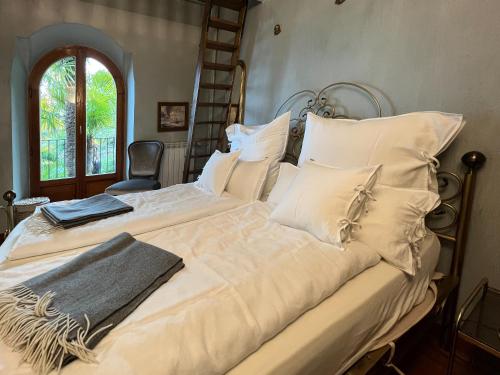 a large bed with white sheets and pillows at Villa Zanotti in Cannero Riviera