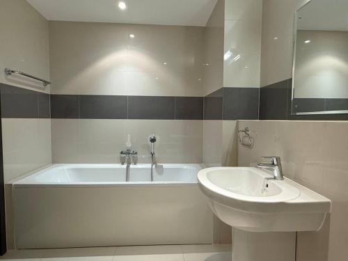 a bathroom with a bath tub and a sink at Thewalk2 Pool View ~ 5 mins from Airport in Seeb