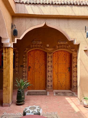 two wooden doors of a building with a potted plant at Dar Dallali maison d'hôtes et excursions in Mhamid