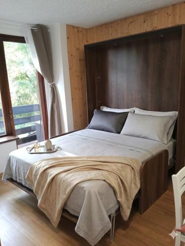 a bedroom with a large bed with a wooden headboard at La Finestra sul Brenta with FREE AND PRIVATE CAR PARK IN MAD di CAMPIGLIO CIPAT O22233-AT-O13262 in Folgarida
