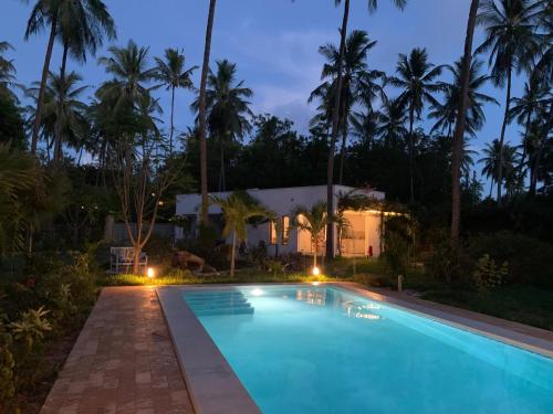 a villa with a swimming pool at night at Nyotas gem in Watamu