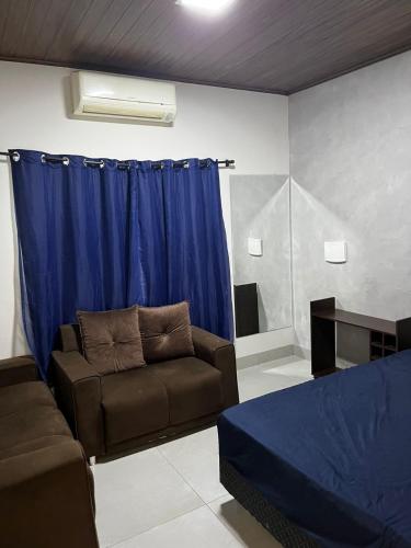 a living room with a couch and blue curtains at Ks Espaço in Rondonópolis