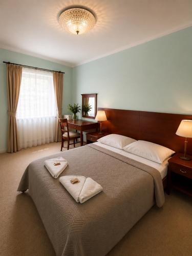 a bedroom with a large bed with two towels on it at Hotel Karolinka in Karpacz