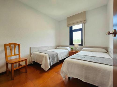 two beds in a room with a chair and a window at URB. PEDRAS NEGRAS in Pontevedra