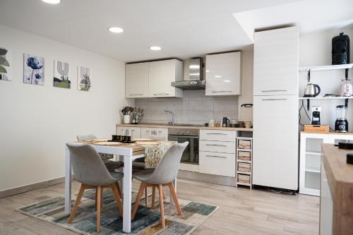 a kitchen with white cabinets and a table and chairs at Domus Home Ladispoli in Ladispoli