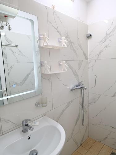 a white bathroom with a sink and a mirror at Vila Erjoni in Ksamil