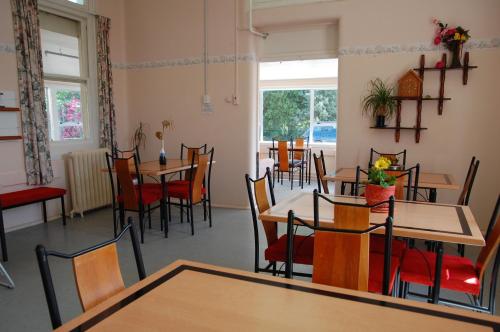 a dining room with tables and chairs and windows at Thomas's Catlins Lodge and Camp Ground in Owaka