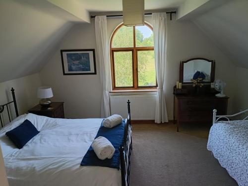 a bedroom with a bed and a window and a mirror at Fig Tree Cottage in Dursley
